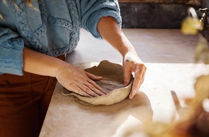 A woman moulding clay with her hands.