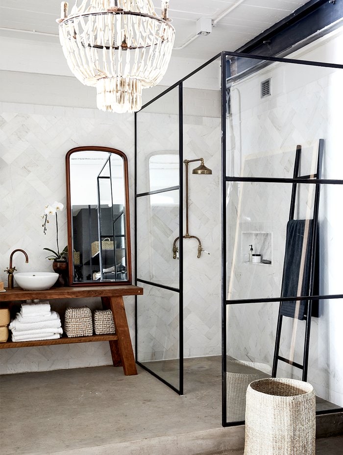 Grey industrial styled bathroom with glass mirrored shower and wooden sink bench
