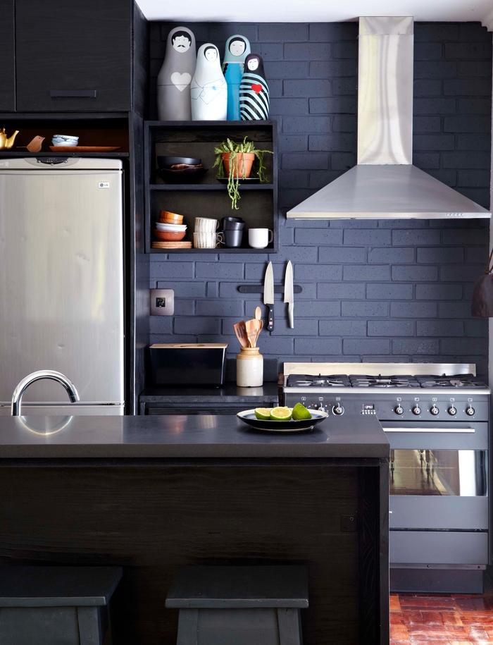 A black kitchen with red brick floors
