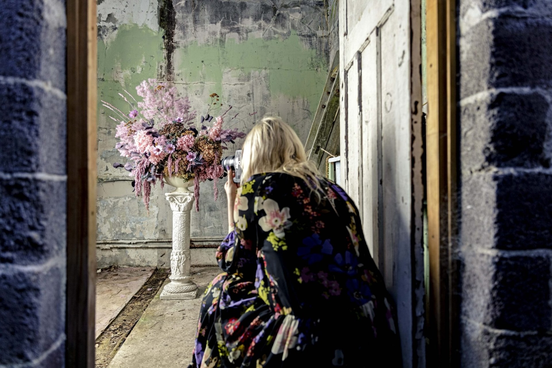 Georgie Malyon taking a photo of a pink and purple dried floral arrangement