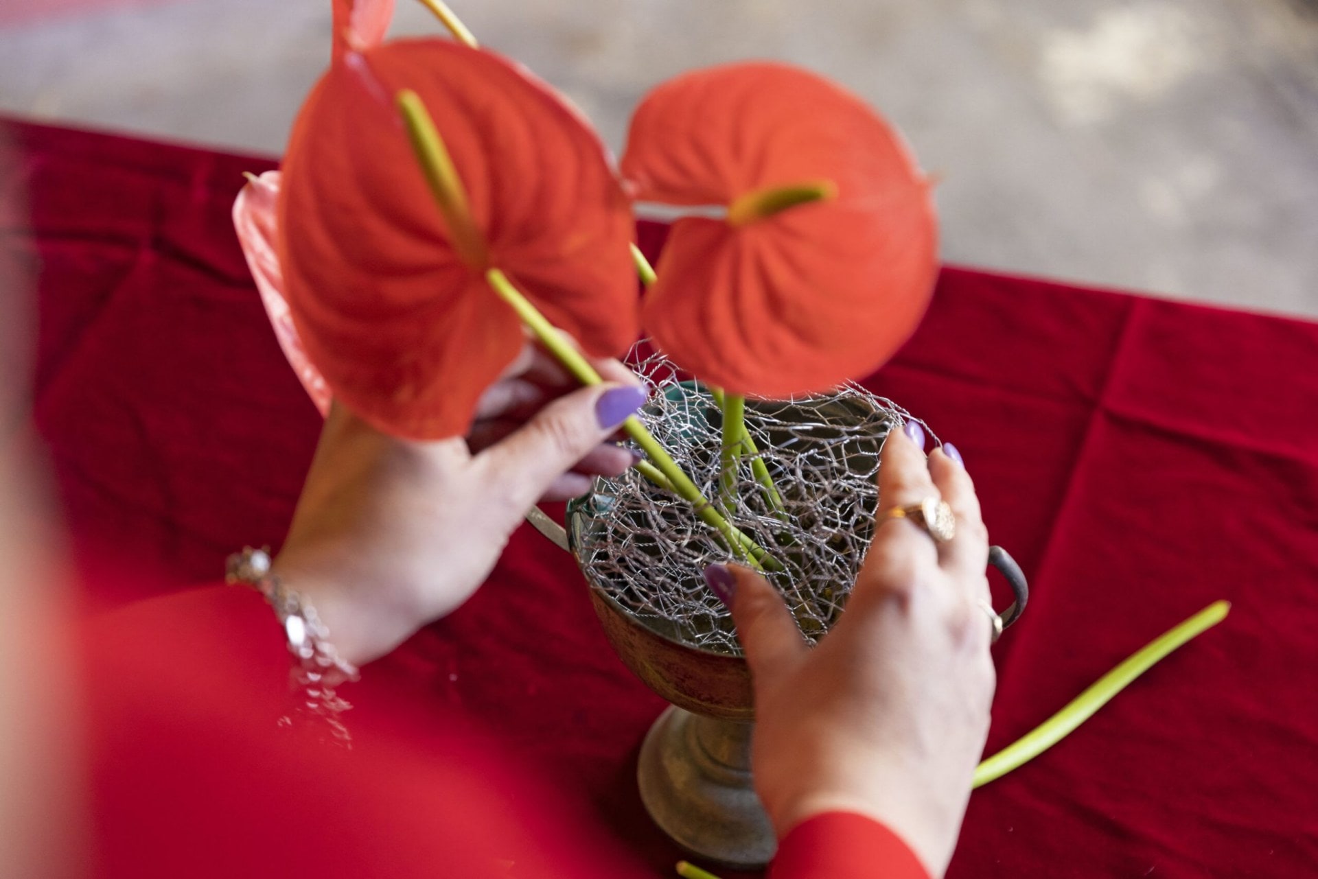 Red flower stems being placed through a ball of chicken wire mesh