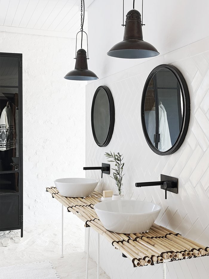 White tiled bathroom with bamboo sink bench and black decorative touches