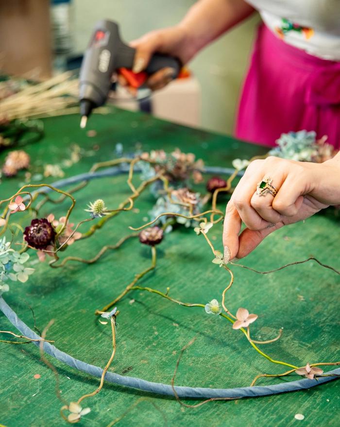 Dried floral wreath being glued on green table