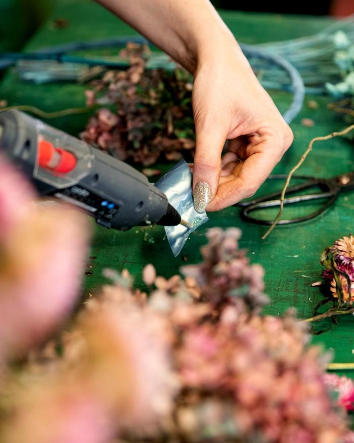 Ribbon being glued on dried floral wreath