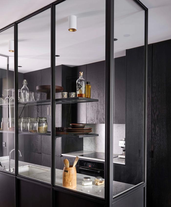 A black kitchen with marble benchtops and glass panelling