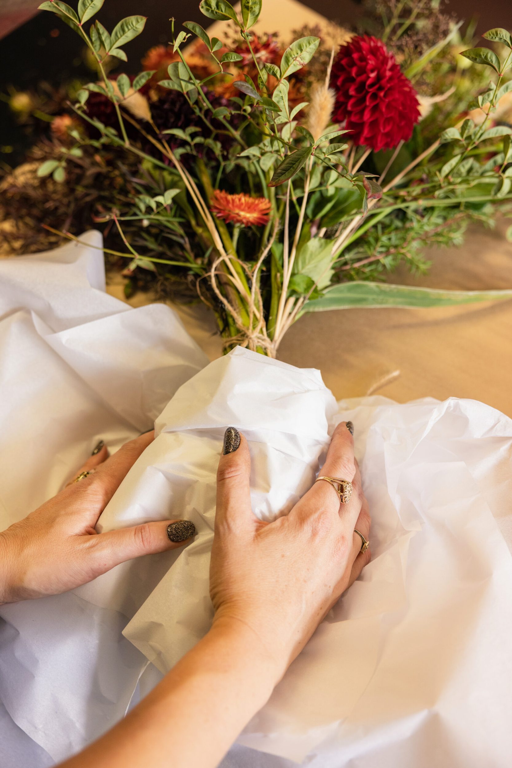 Bouquet of flowers being wrapped in white tissue paper