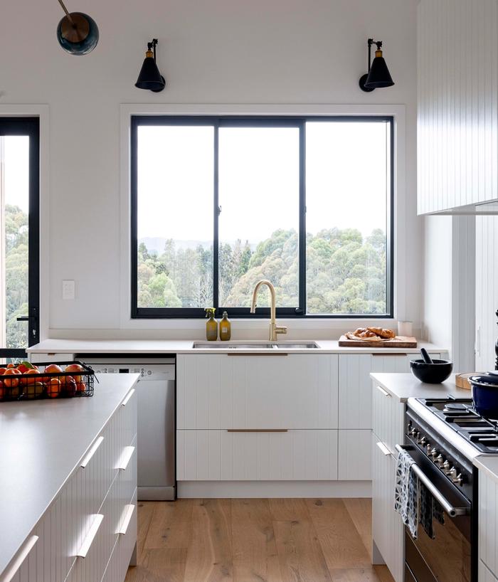 white kitchen featuring grooved cabinets, with timber floors, and a large window with black wall lights on either side