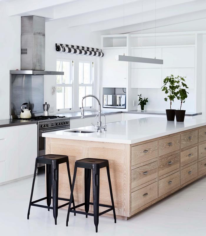 white kitchen with a timber island and black stools