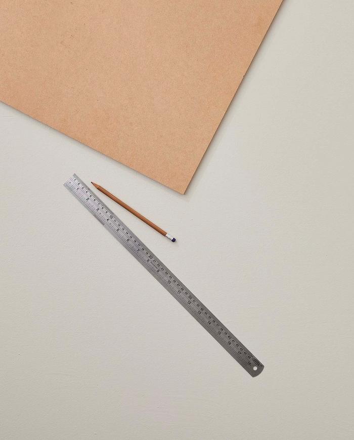 A piece of MDF board with a ruler and a pencil next to it