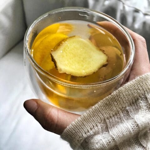 Hand holding glass filled with ginger tea