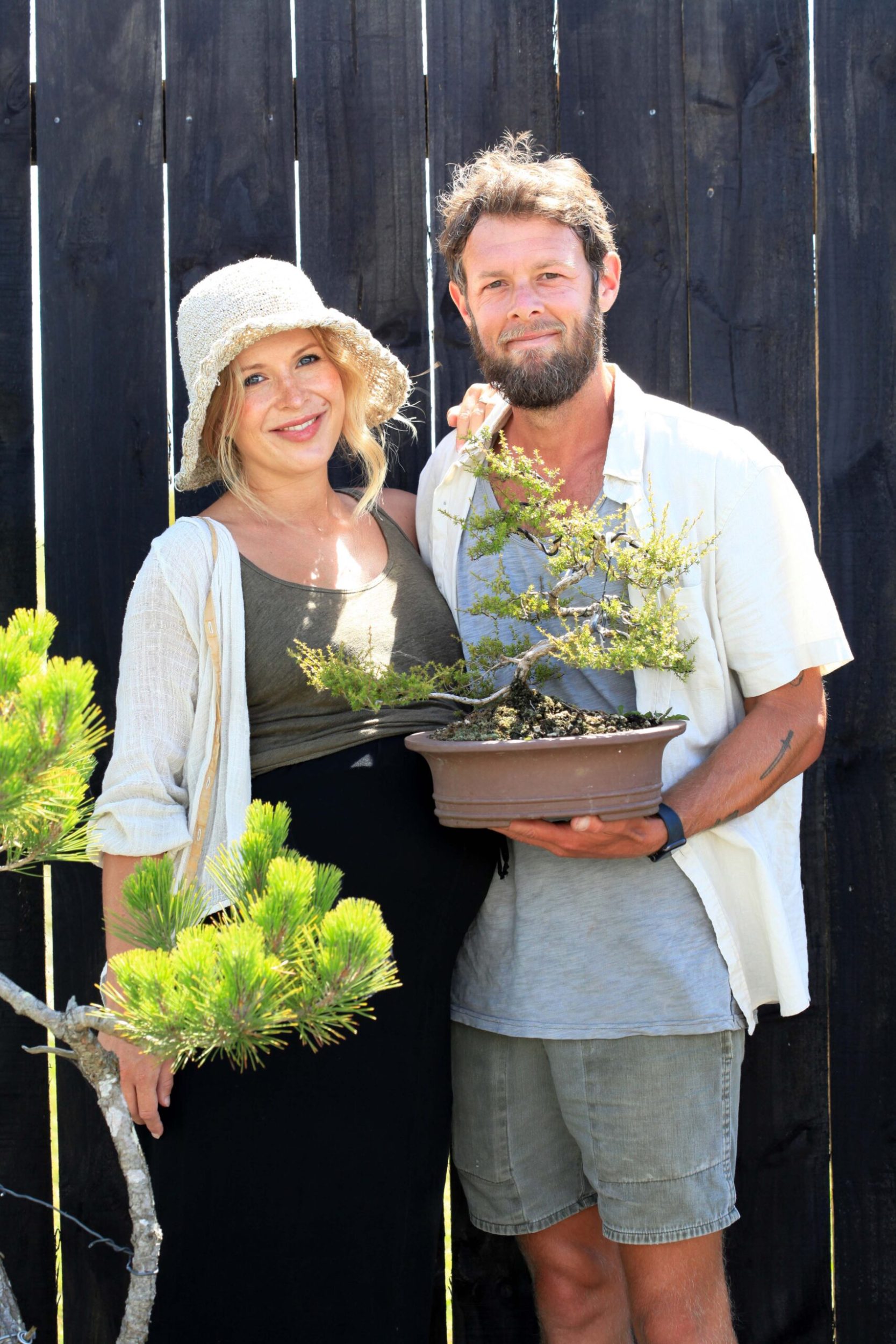 Adrian Bird and Nora Bird standing in garden holding bonsai tree
