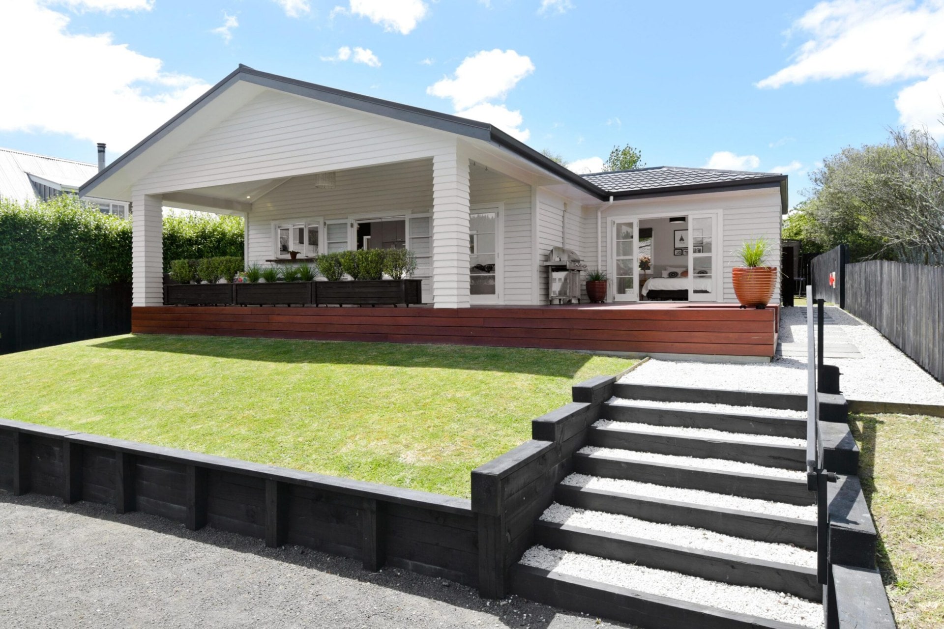 A home with white cladding and a black gabled roof