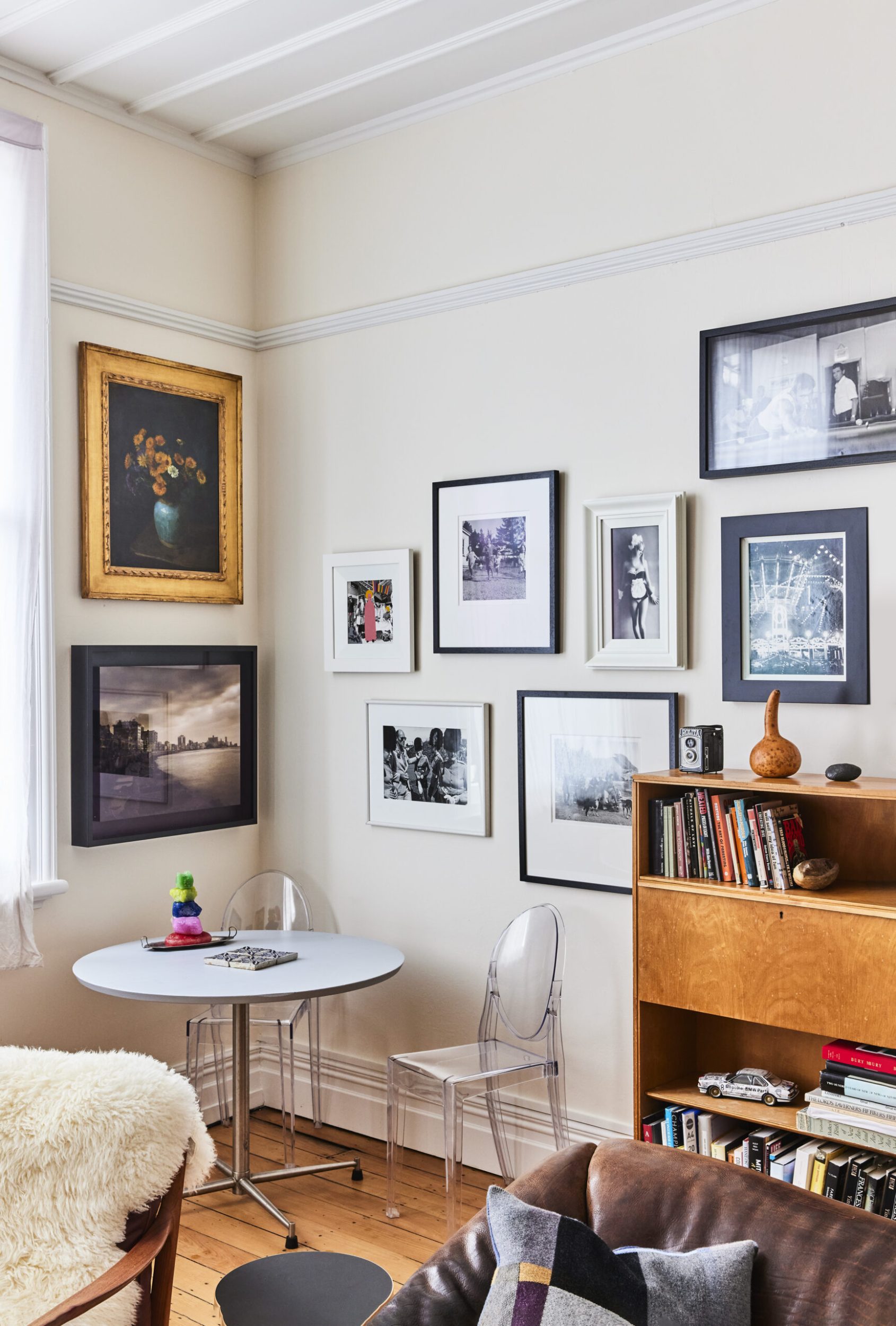 Corner of a white room with assorted paintings and black and white photographs by Ans Westra