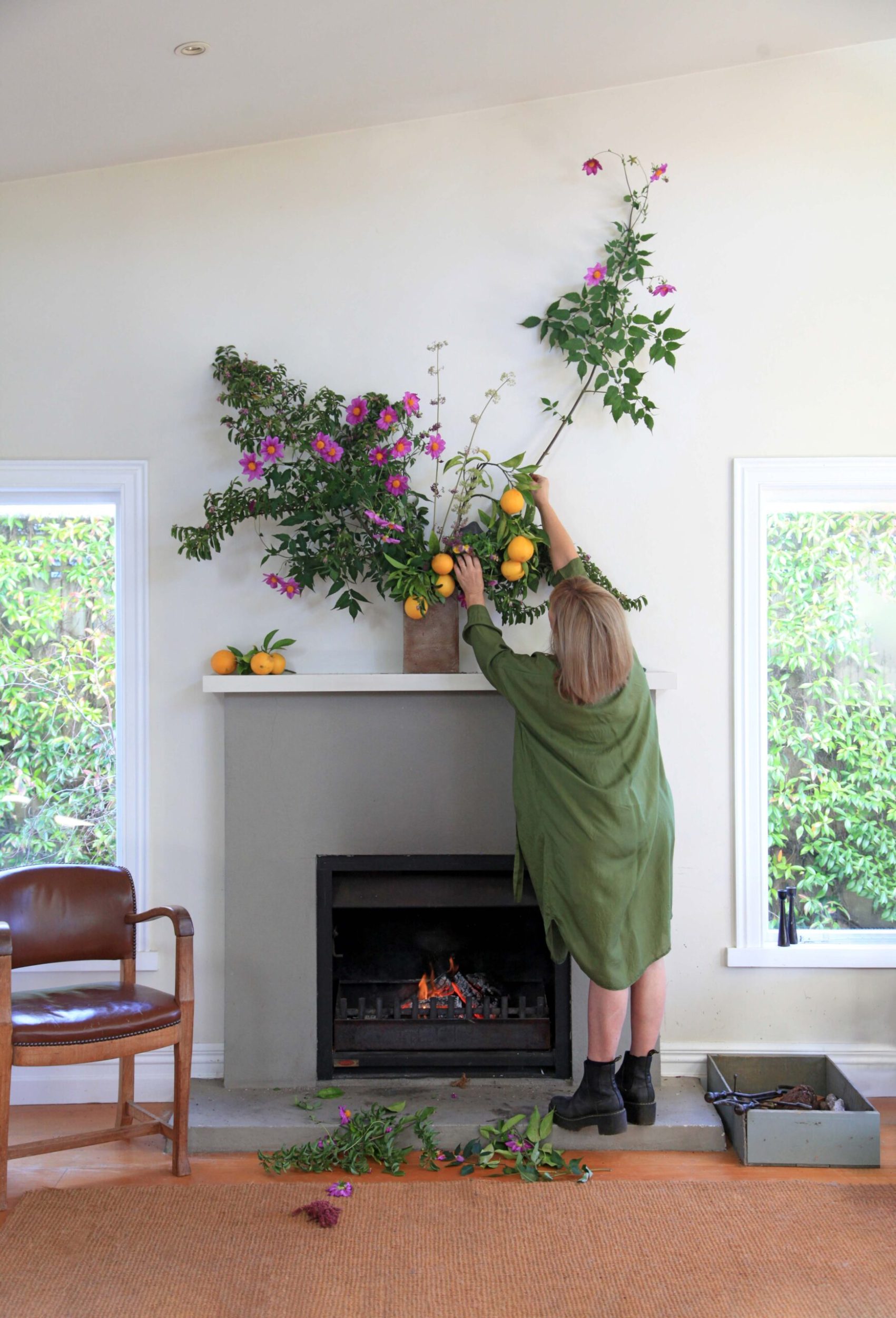 Felicity Jones arranging a floral arrangement set above a fireplace