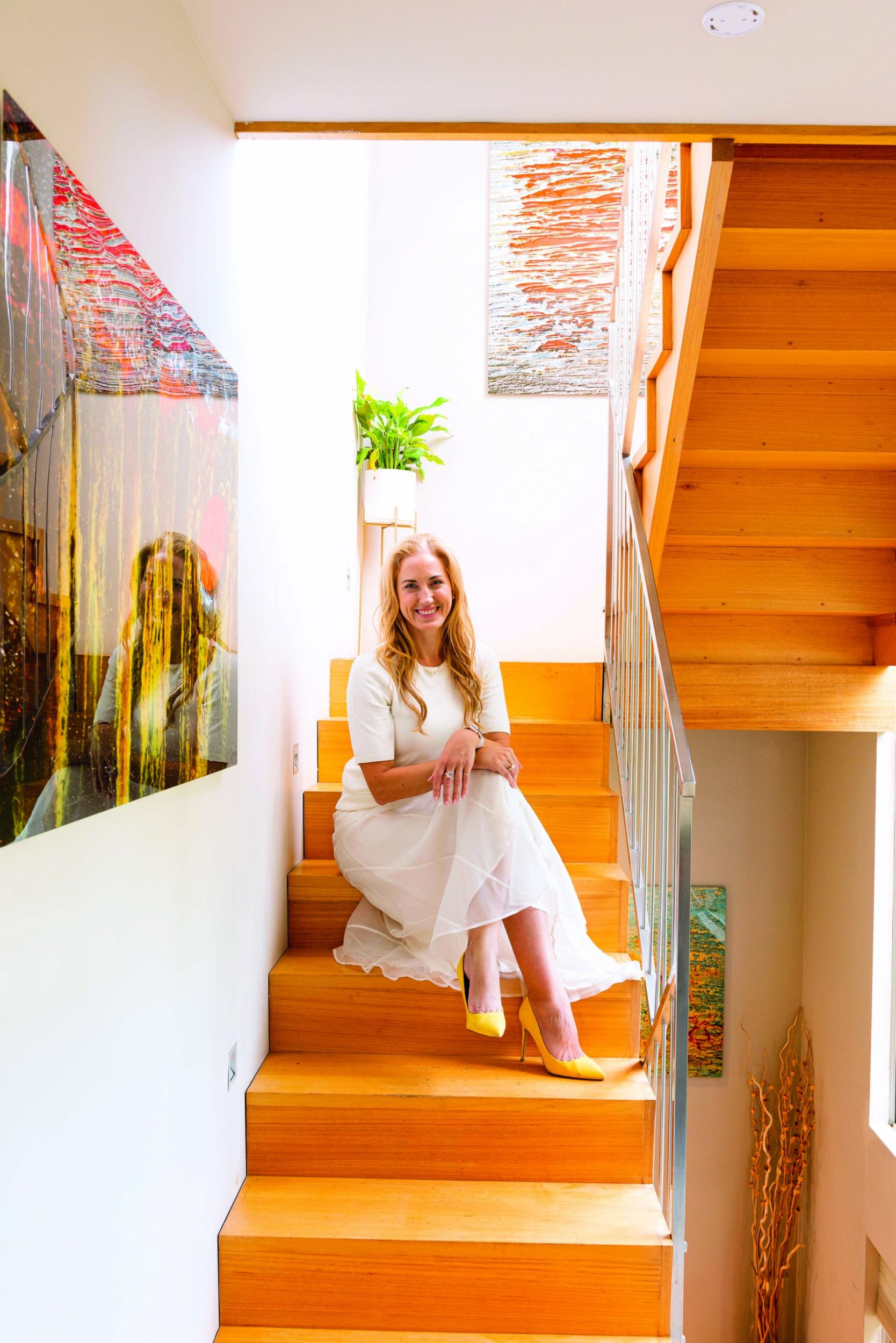 Dr Catherine Stone wearing white dress sitting on wooden steps