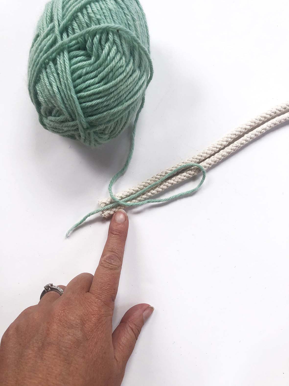 A finger holding a piece of string next to a cord