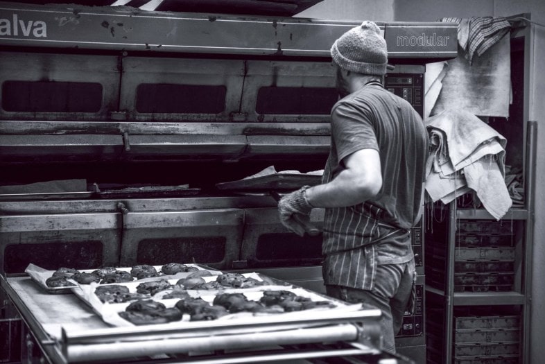 Black and white photo of bread being baked in bakery