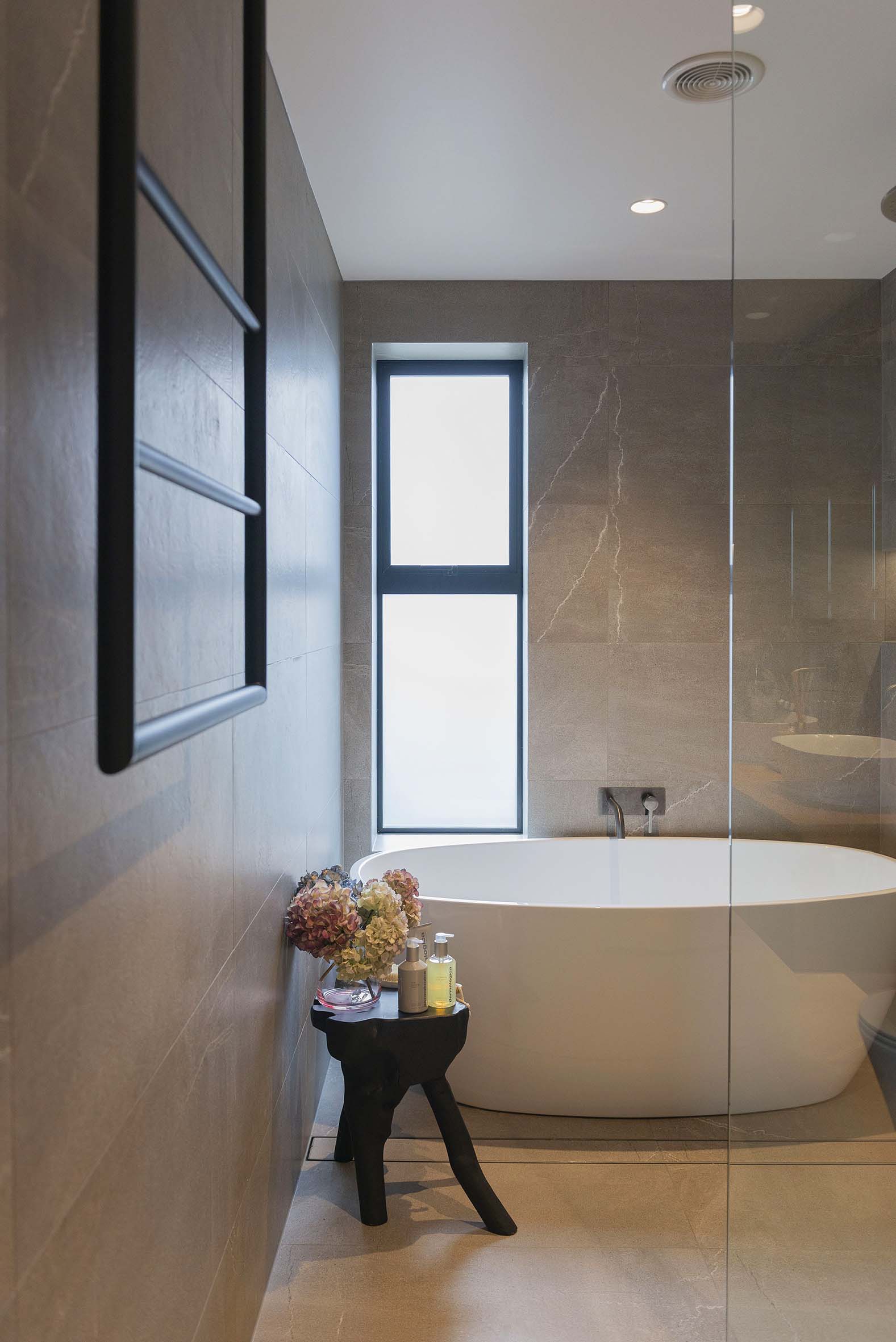 Bathroom with light grey tiles and a large bathtub