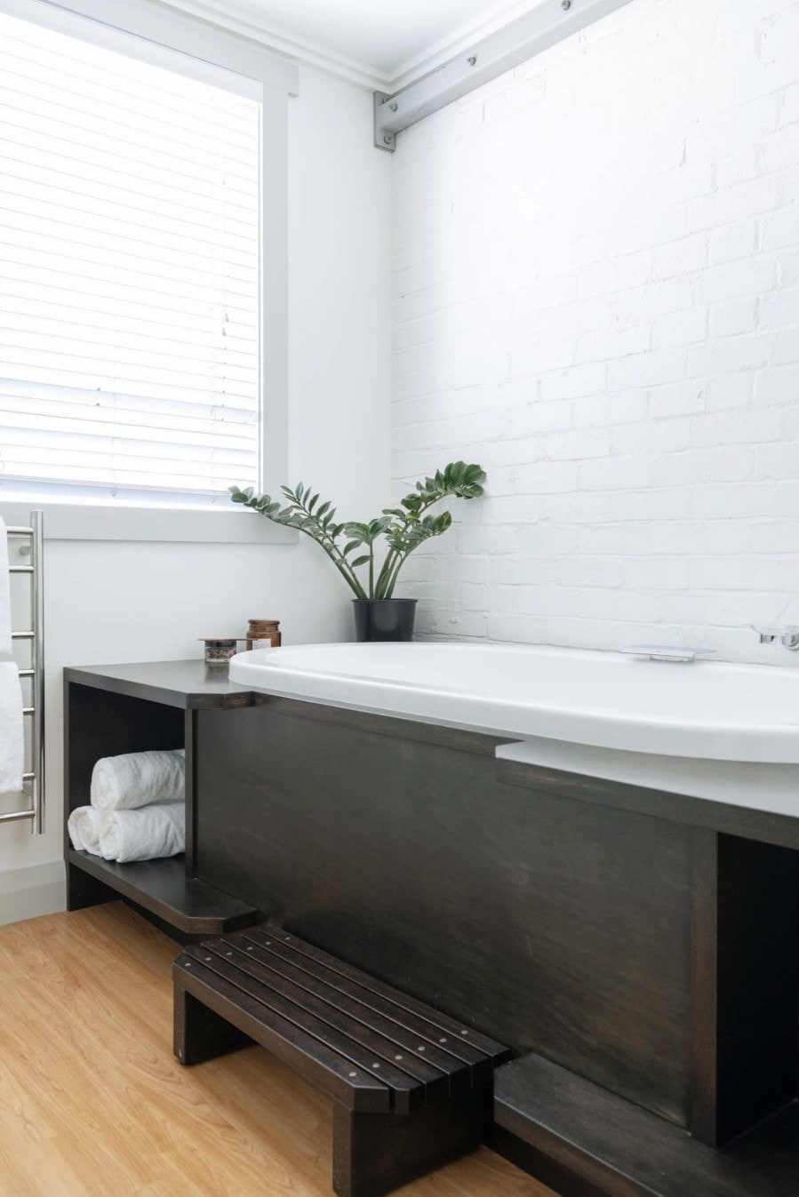 Bath with a black wooden frame and white brick wall