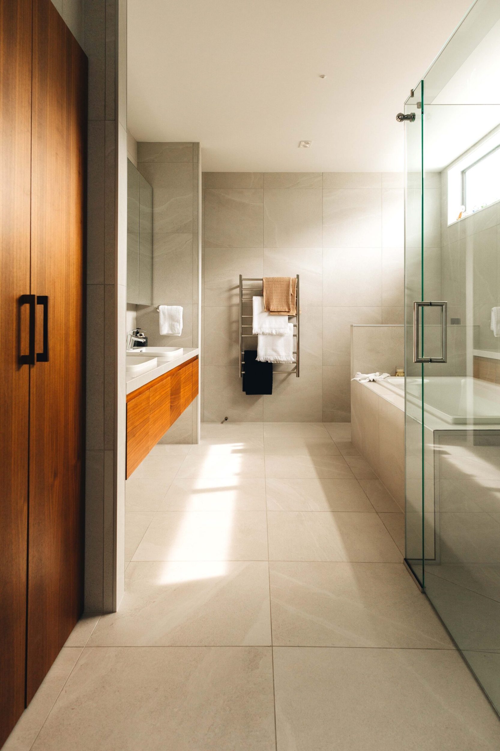 Bathroom with grey floor and wall tiles and wood cabinets and a door