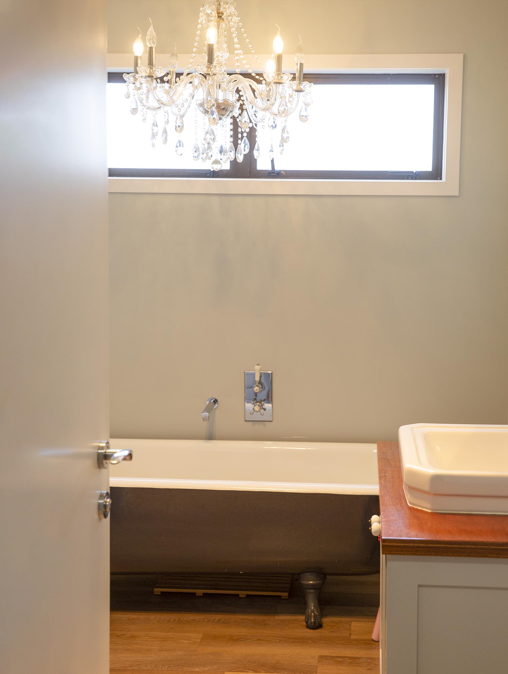 A bathroom with an old clawfoot bathroom and hanging chandelier