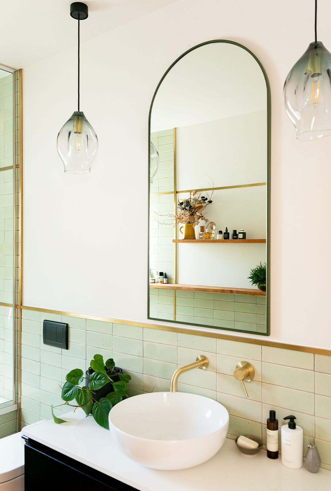 White and green bathroom with large gold brass rounded mirror