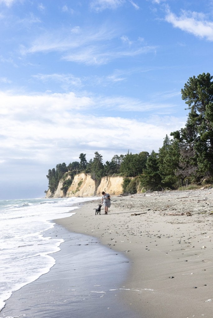 Fleur Woods walking along Kina Beach with dog George