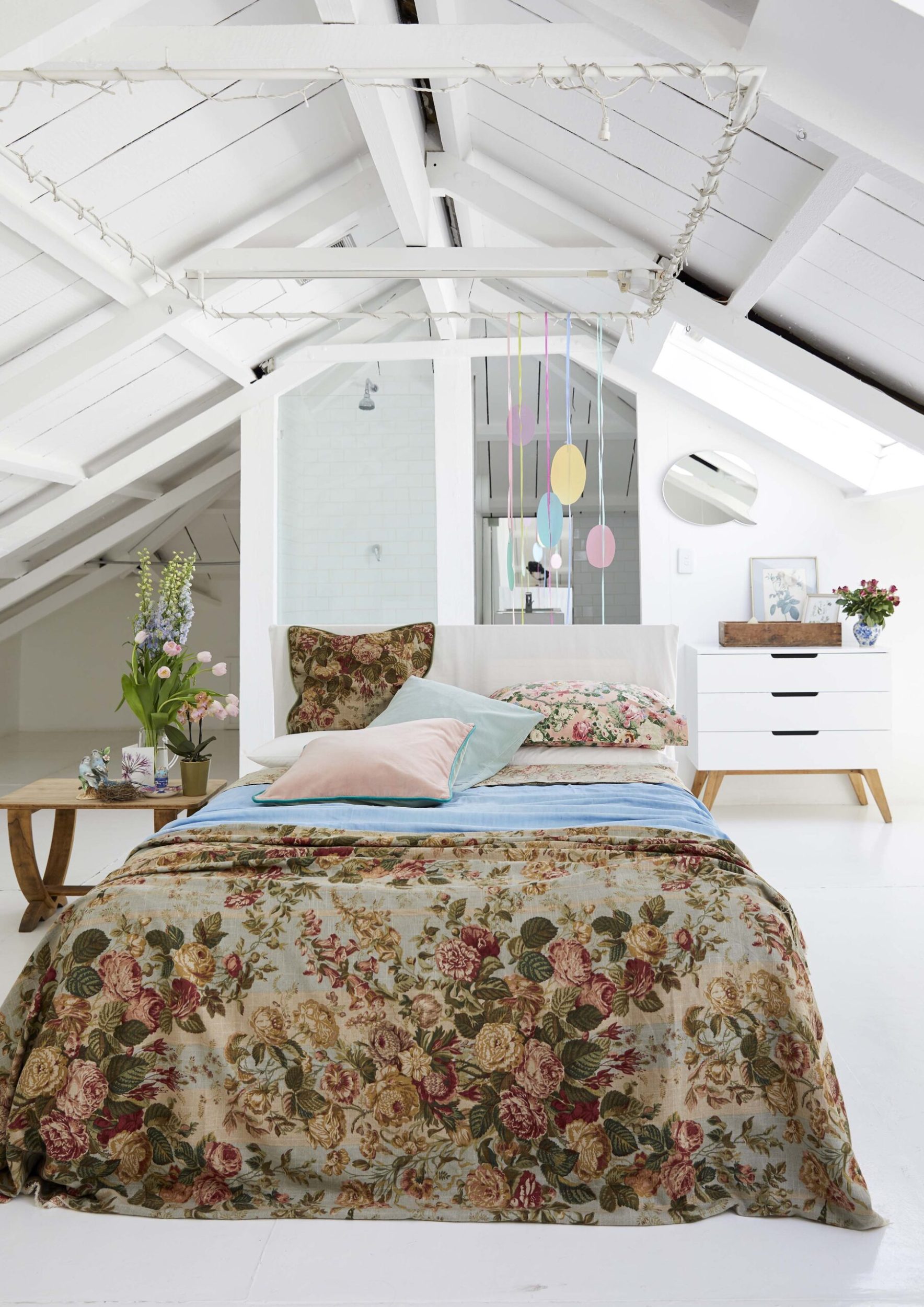 A bed in the middle of a white room with a floral bedspread