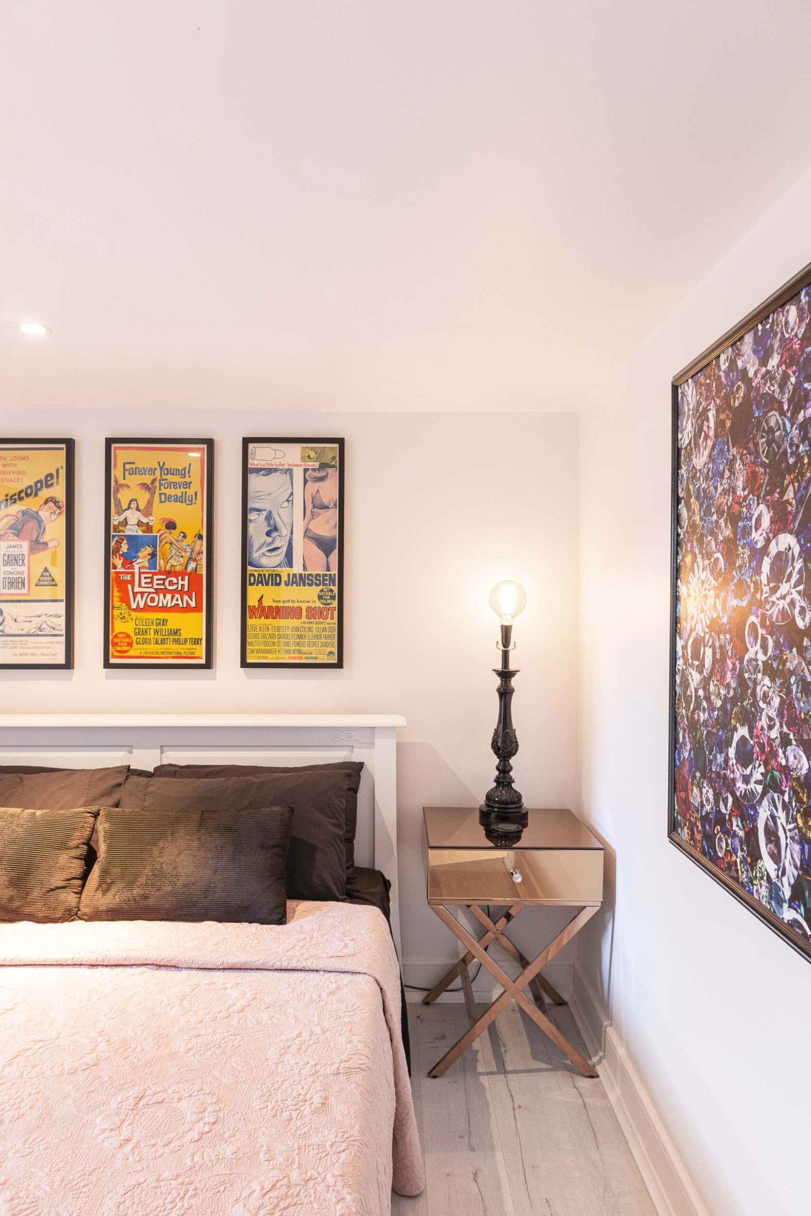 Corner of bedroom with three framed posters and art on walls