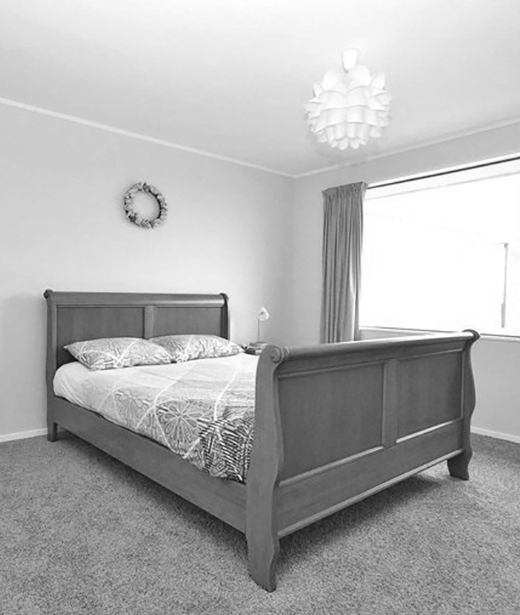 A black and white photo of a bedroom with a queen sized bed