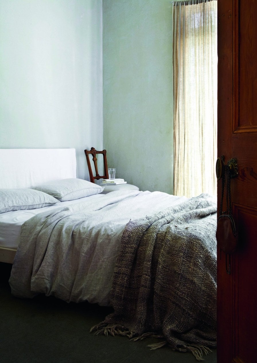 Bedroom with grey walls, a grey duvet and cream muslin curtains