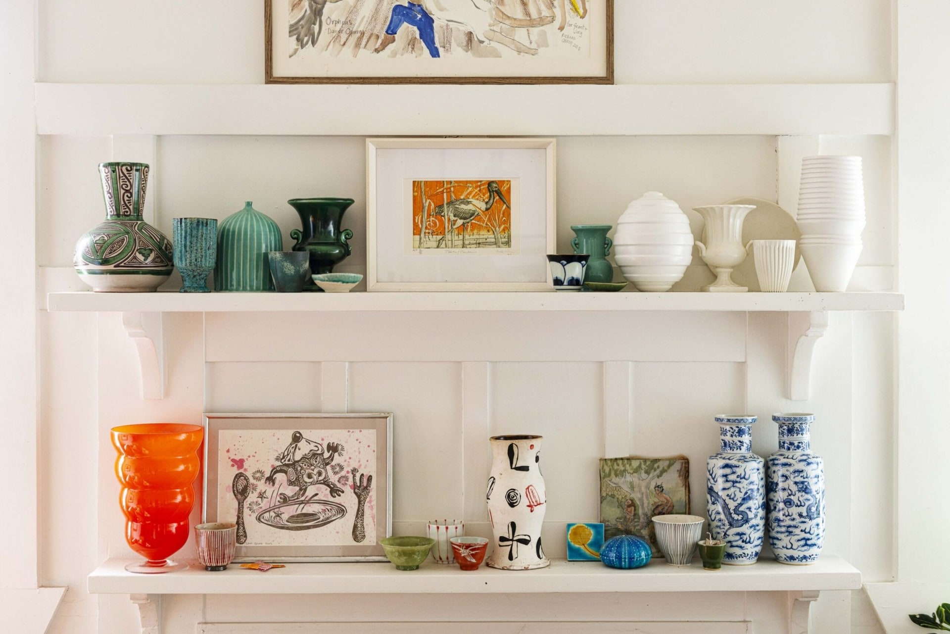 A white wall with white benches with various vases and art