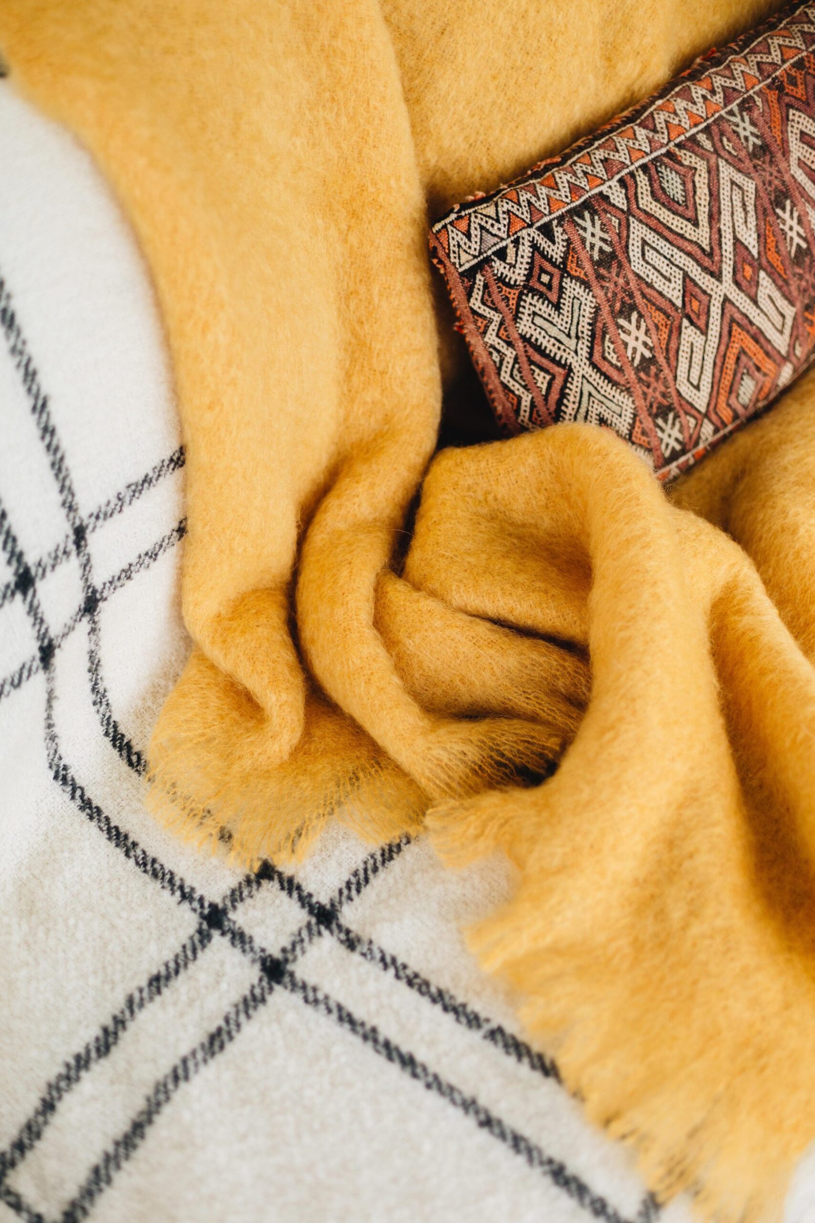 A mustard yellow Masterweave blanket lying on top of a black and white striped Masterweave blanet