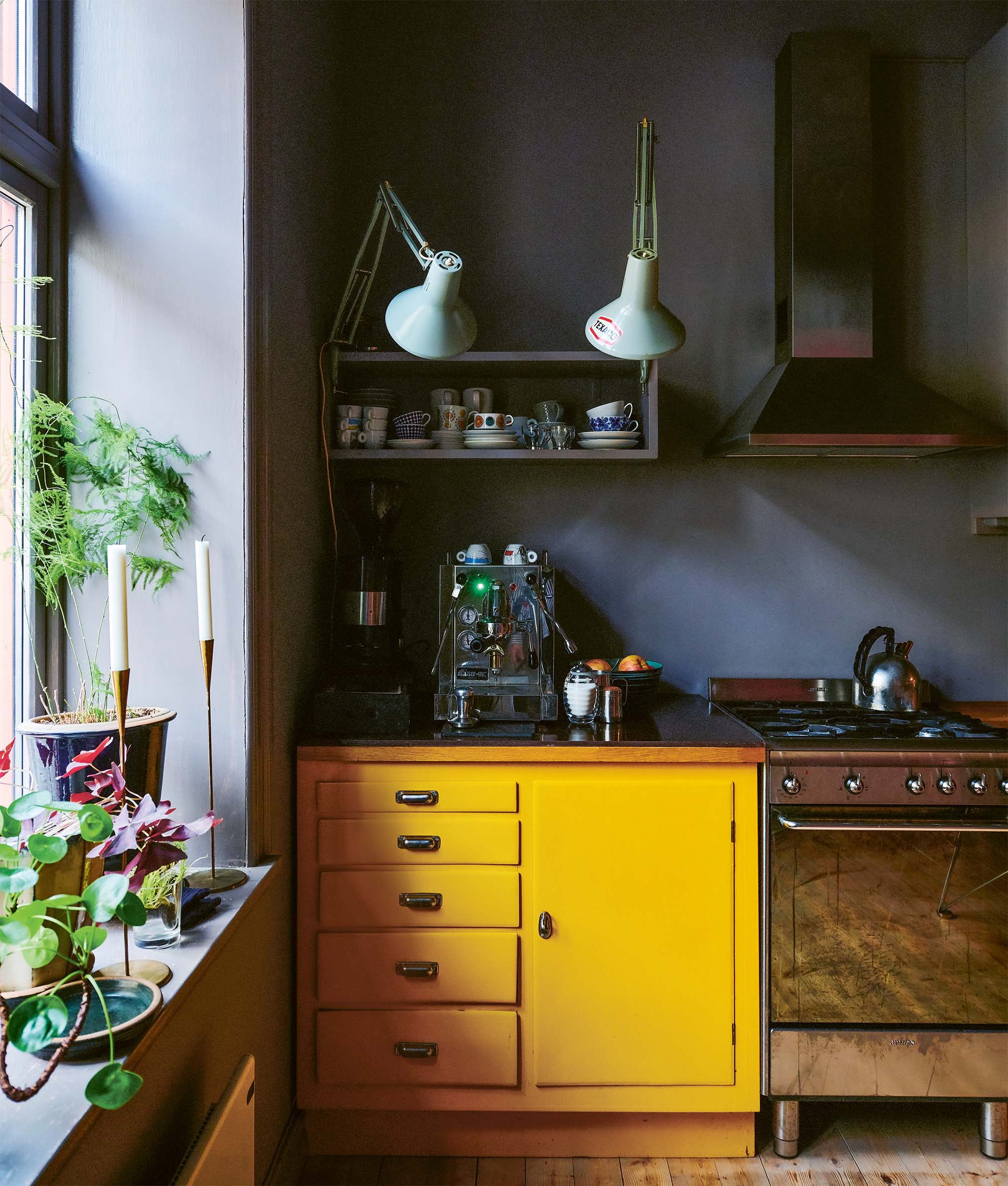 Kitchen with black walls, yellow cabinet and plants on windowsill
