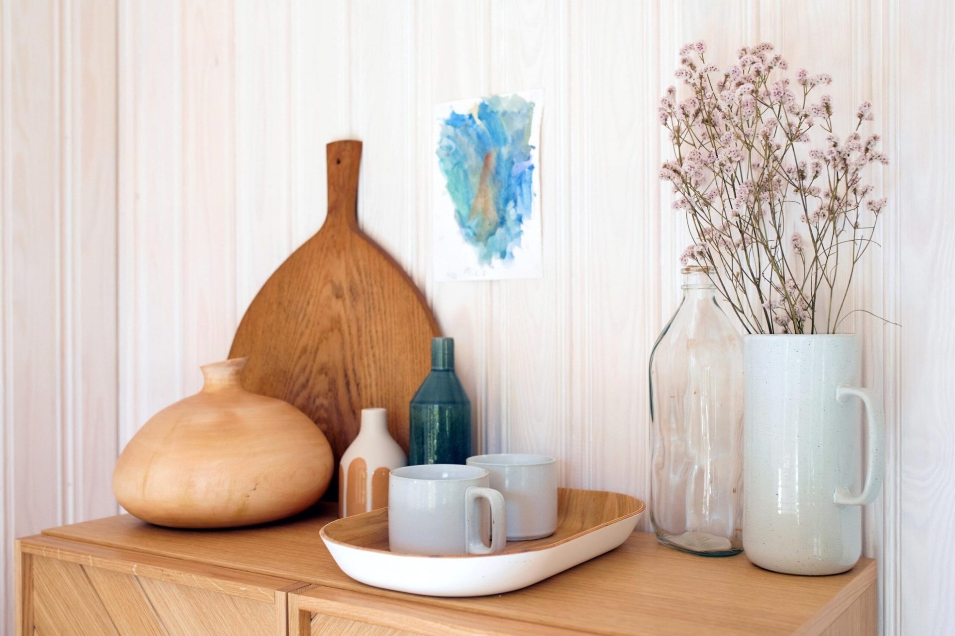 Wood and glass cups and vases on top of a light wood drawer