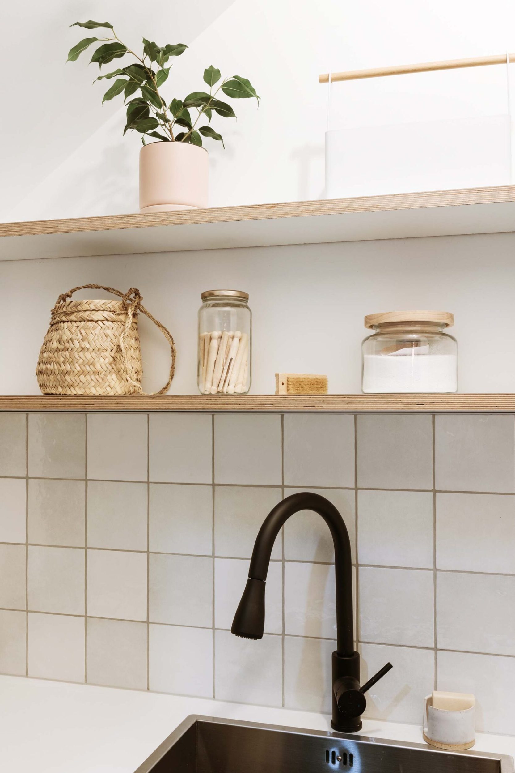 A black sink in a bathroom with wooden shelves