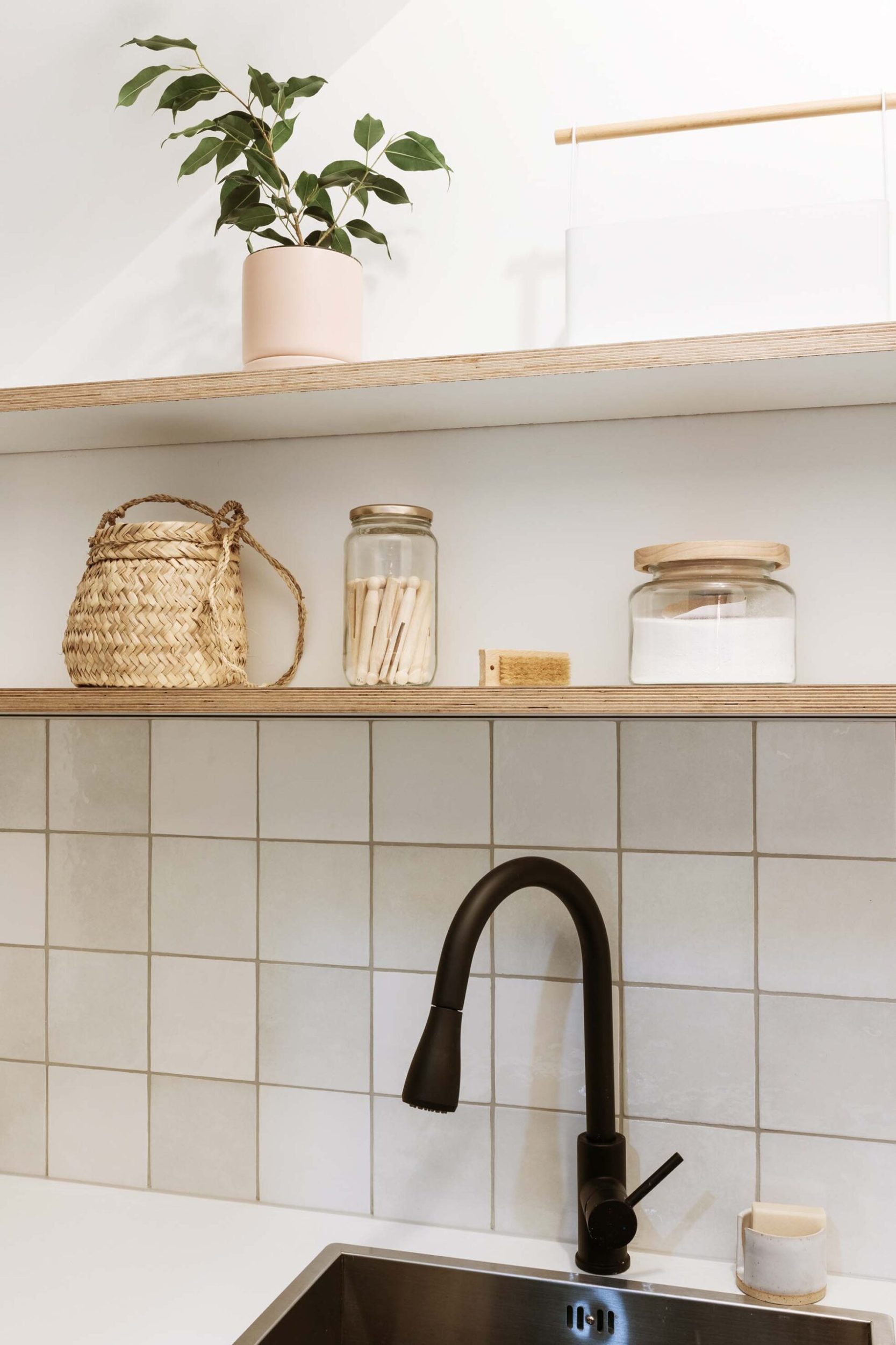 A black sink in a bathroom  with wooden shelves