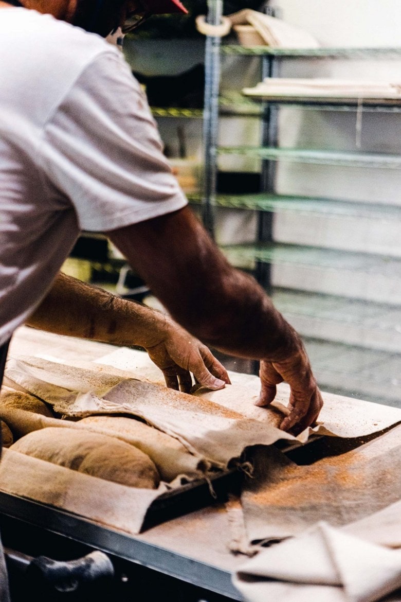 A person laying bread dough onto a baking tray