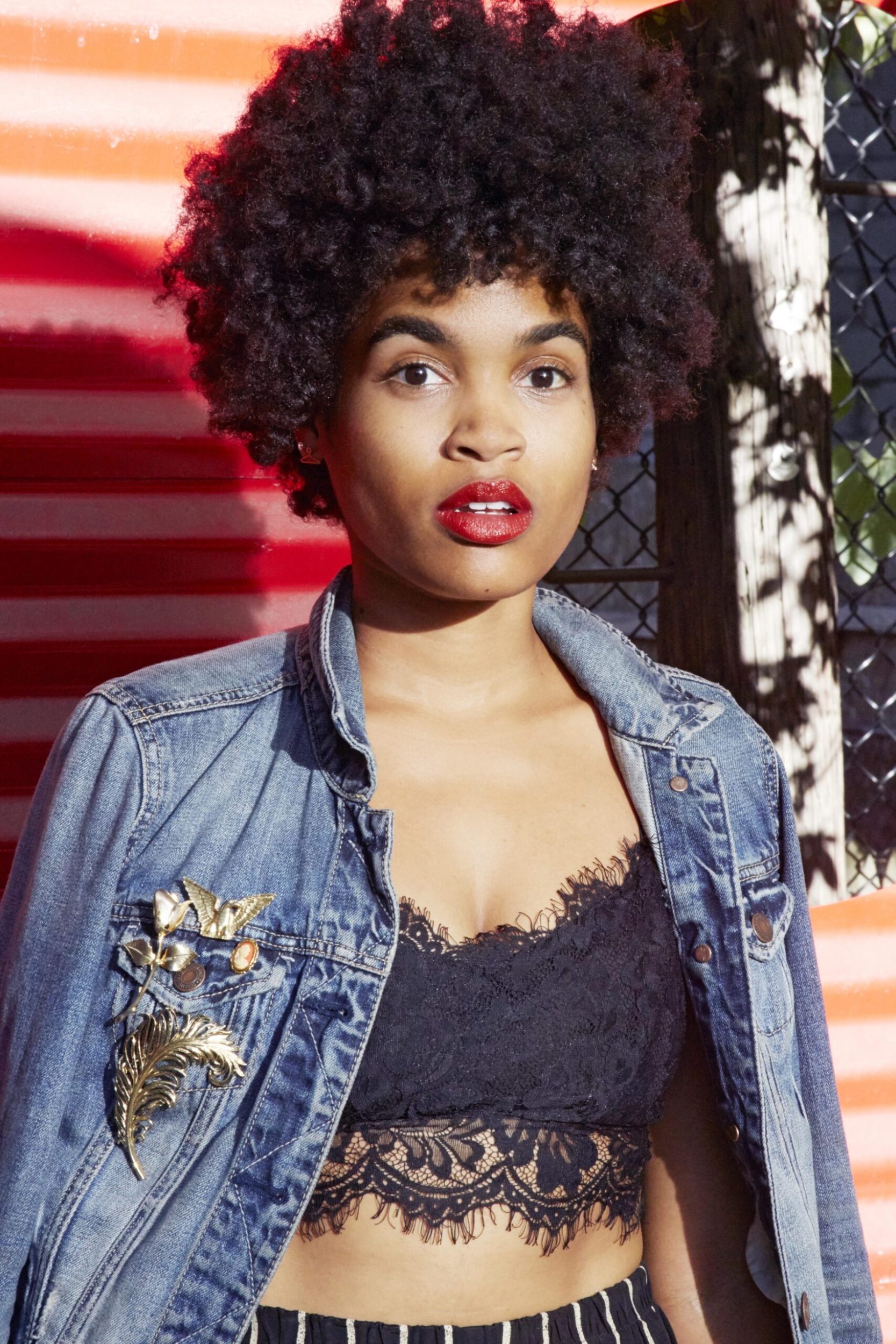Woman wearing blue jean jacket with gold broaches covering holes