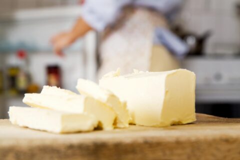 A block of butter with slices cut out on a wooden board