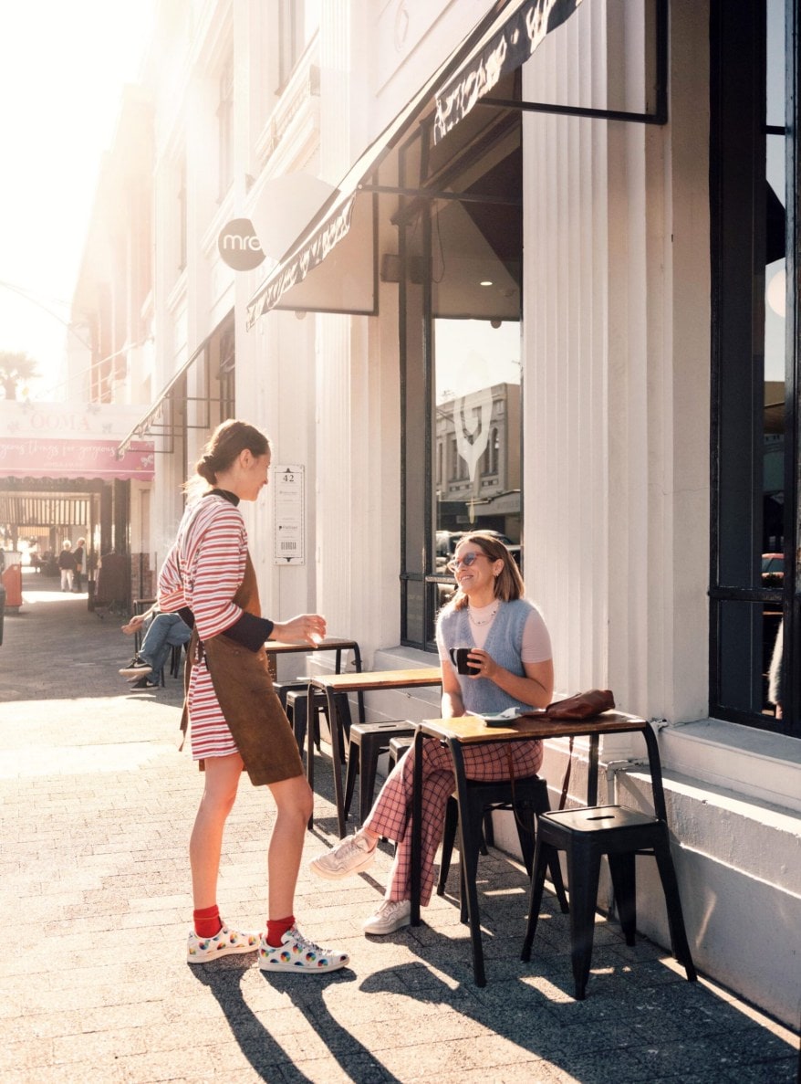 Danni Duncan sitting outside of Cafe Tennyson smiling while talking to a waitress