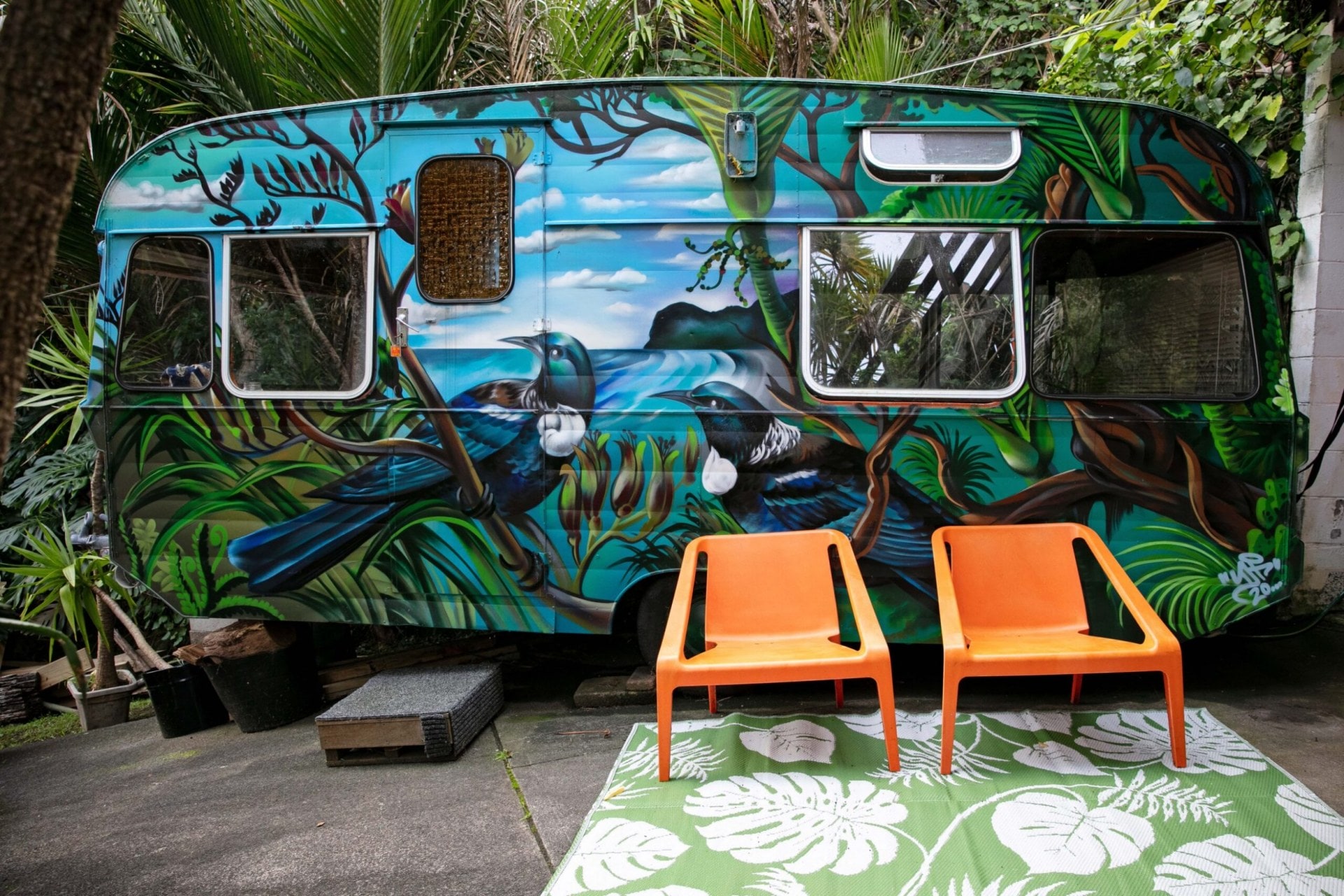 Classic caravan painted with two large tui birds and New Zealand beach landscape