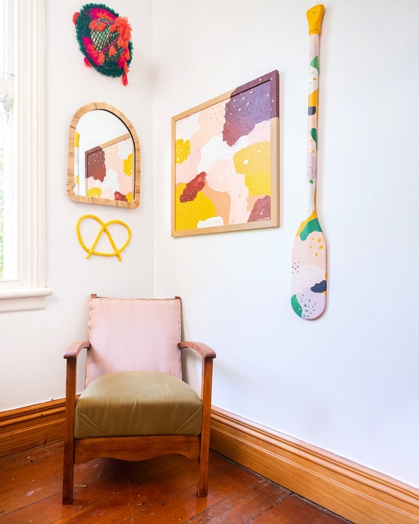 Pink and green chair in room corner with abstract art by Alice Berry hanging on walls