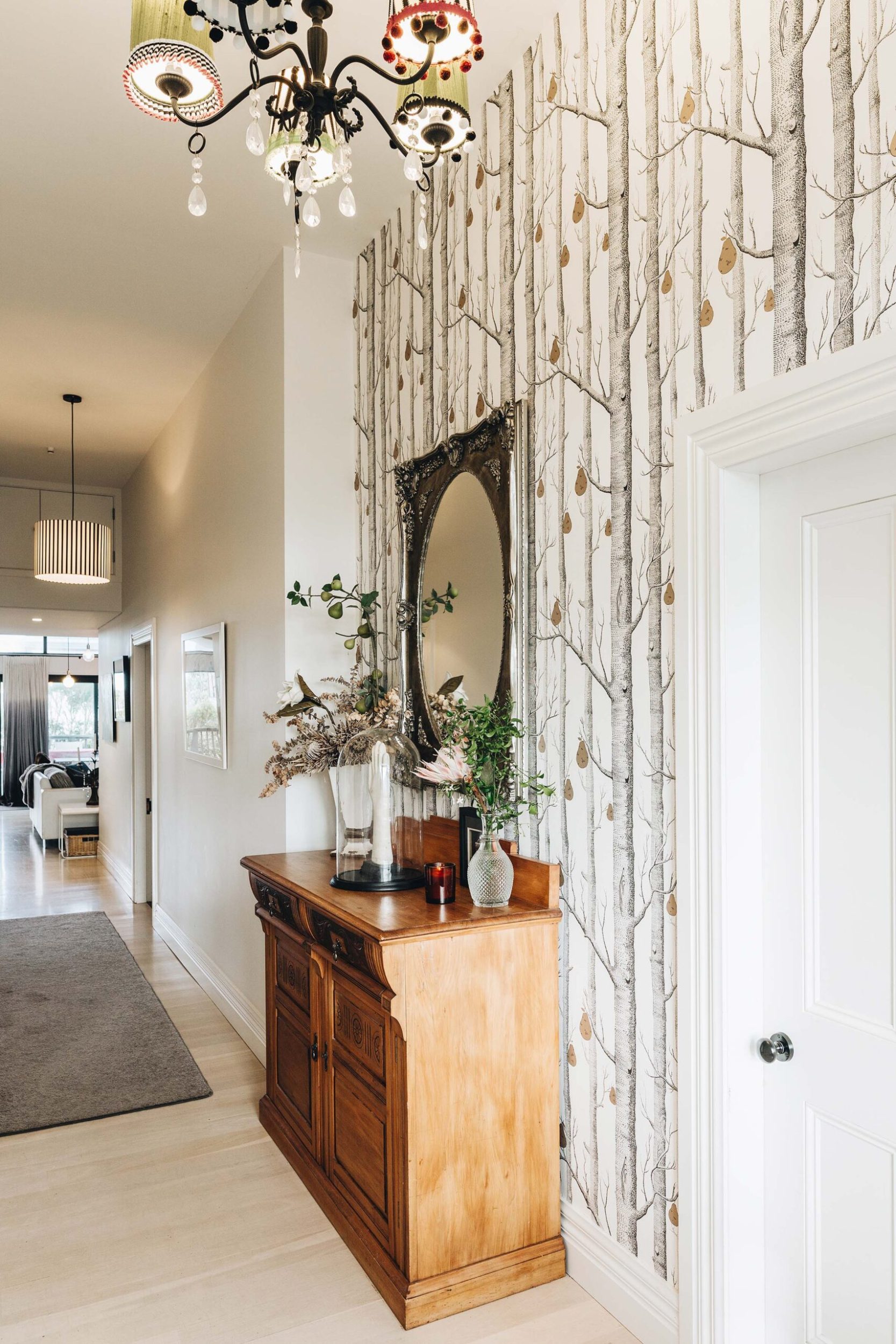 Karen Delehanty's hallway with a chandelier, rimu dresser and black, white and gold wallpaper