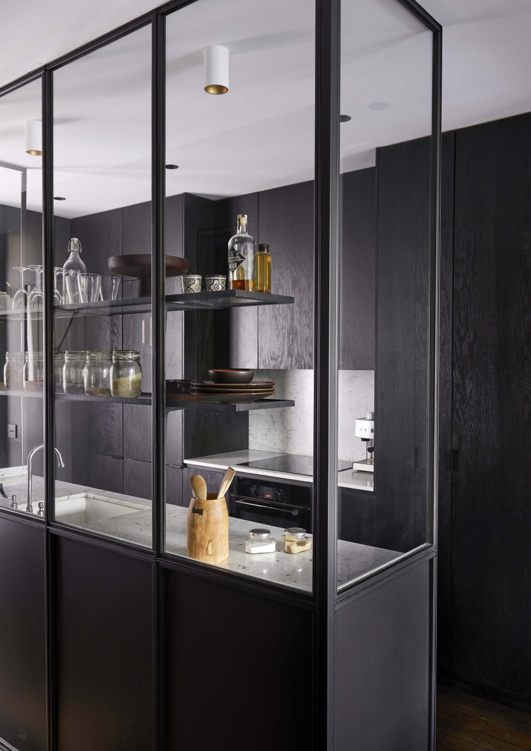 A black kitchen with marble benchtops and glass panelling