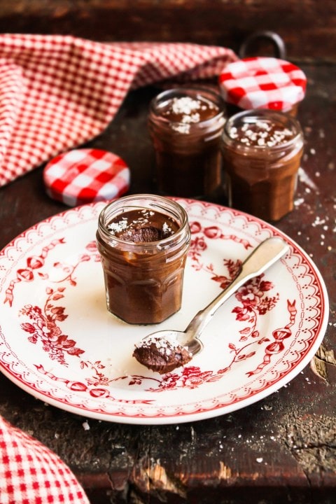 Chocolate mousse in a glass jar served on a round plate with a spoon