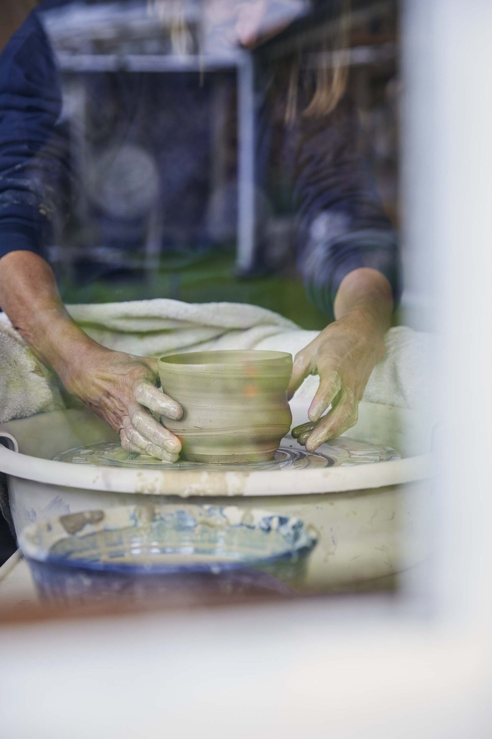 A close up Elena Renker's hands creating a bowl on a clay wheel