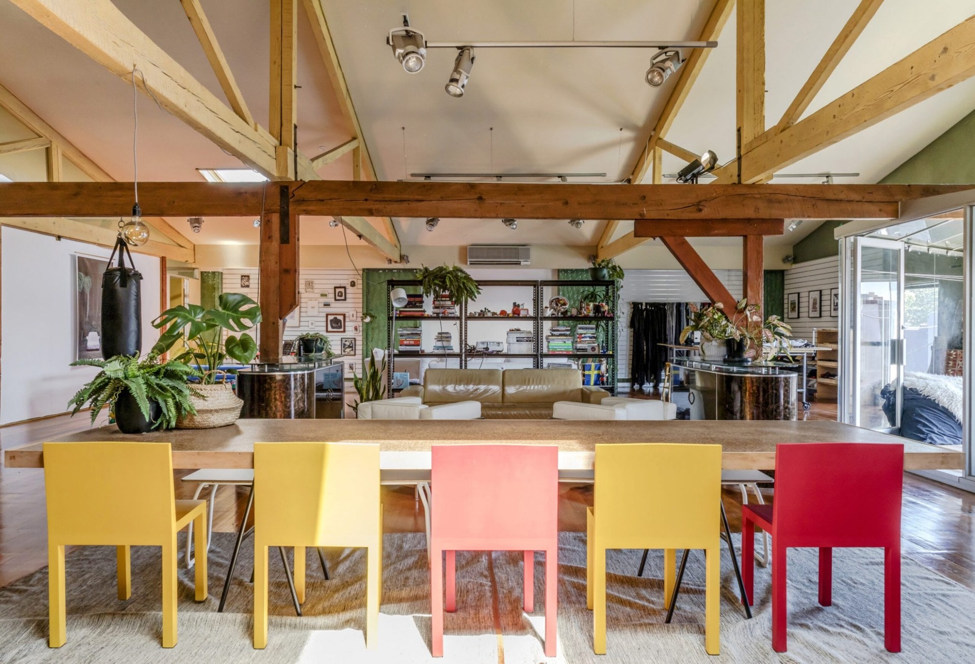 Large room with wooden means, a brown dining table and red and yellow chairs 