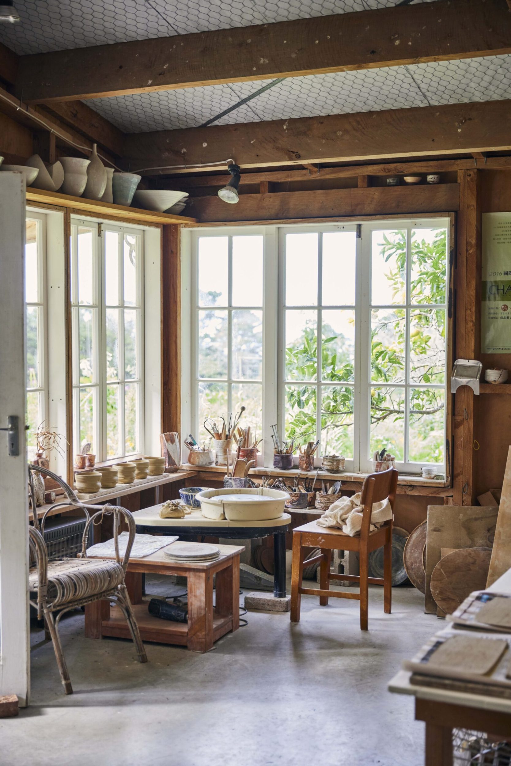 A corner of a room with square windows and a brown table filled with ceramics