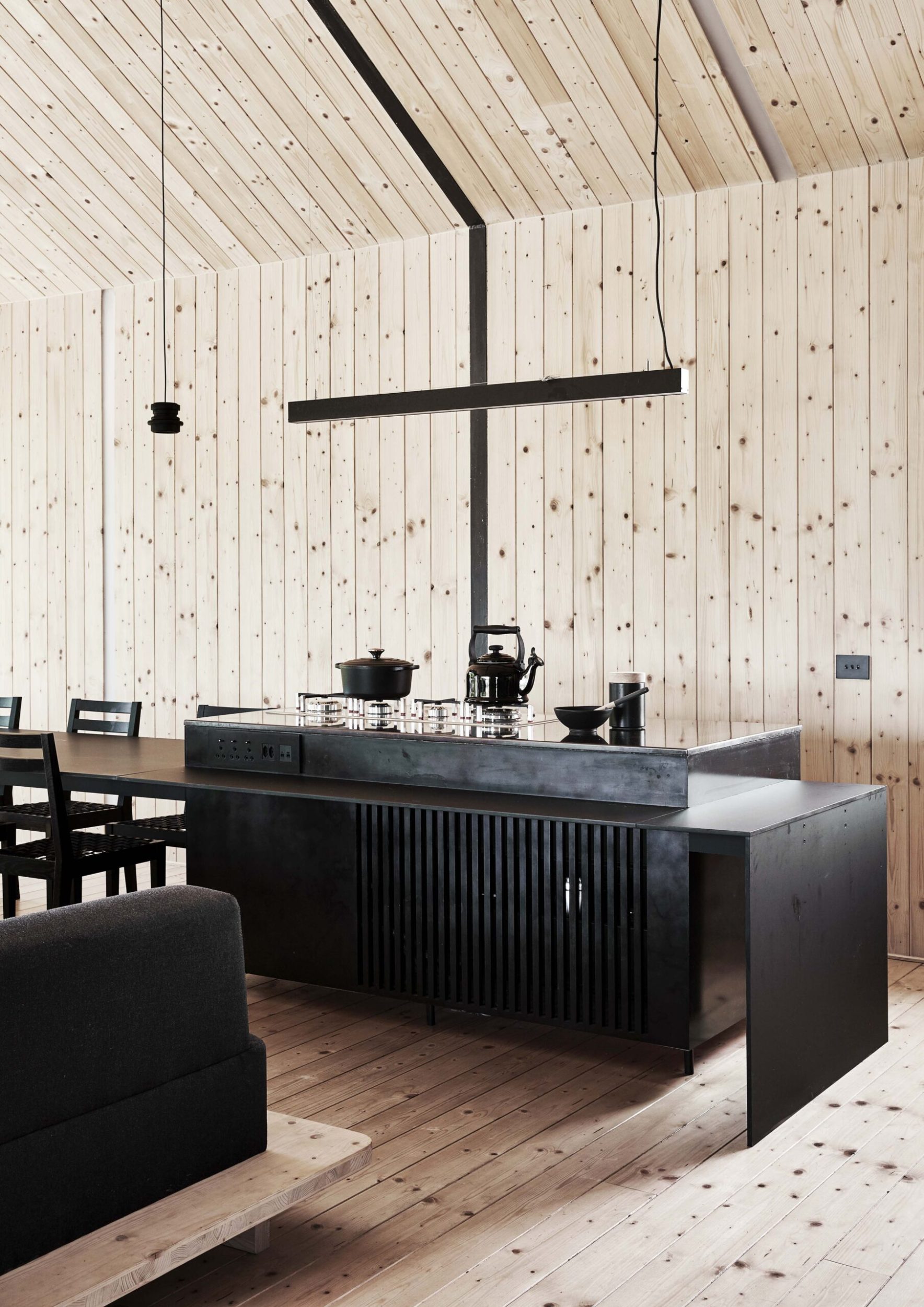 A kitchen with wood panels and floors and a dark benchtop